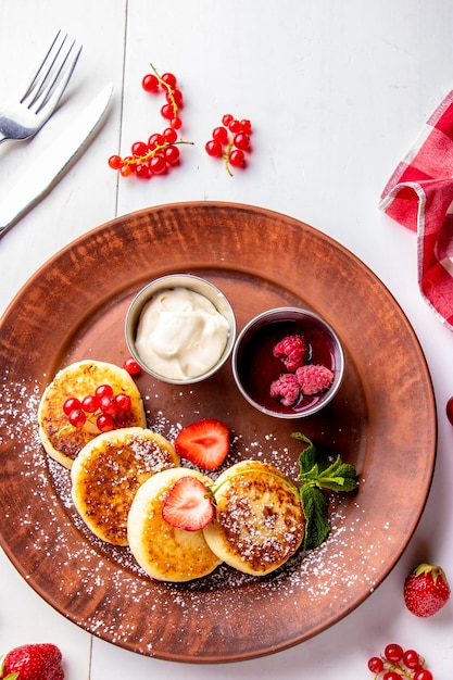 Cottage cheese pancakes homemade traditional Ukrainian dish syrniki with berry sauce and sour cream