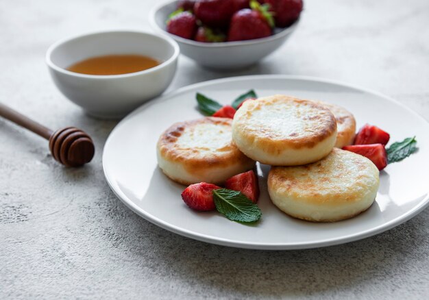 Cottage cheese pancakes ricotta fritters on ceramic plate with  fresh strawberry