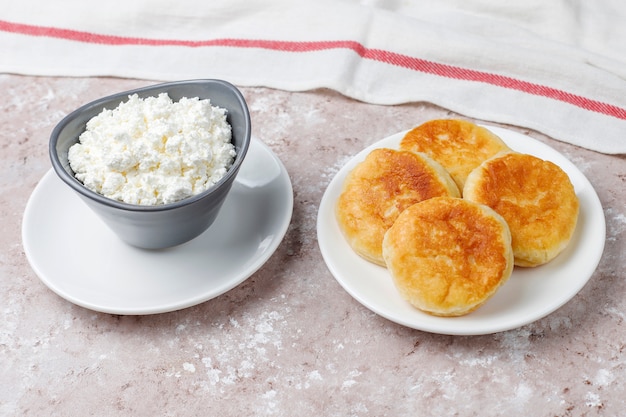 Frittelle di ricotta syrniki russo o sirniki, frittelle di ricotta o pancake con una ciotola di ricotta fresca fatta in casa