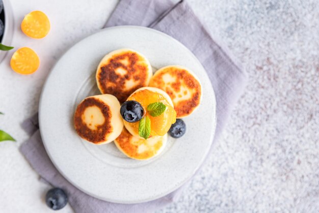 Photo cottage cheese pancakes sweet curd fritters with blueberry and physalis