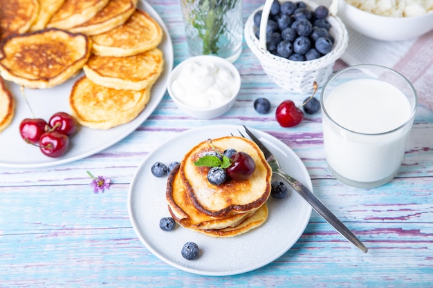 Cottage cheese pancakes (syrniki). Homemade cheesecakes from cottage cheese with sour cream, berries and milk. Traditional Russian dish. Close-up.