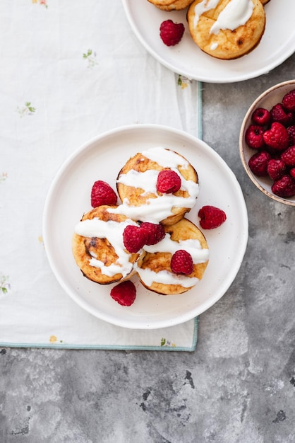 Cottage cheese pancakes in white plate Syrniki with raspberries and sour cream