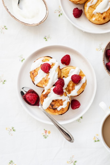 Cottage cheese pancakes in white plate Syrniki with raspberries and sour cream