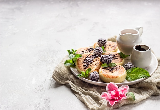 Cottage cheese pancakes with berries, chocolate and mint. Syrniki. Gourmet Breakfast.