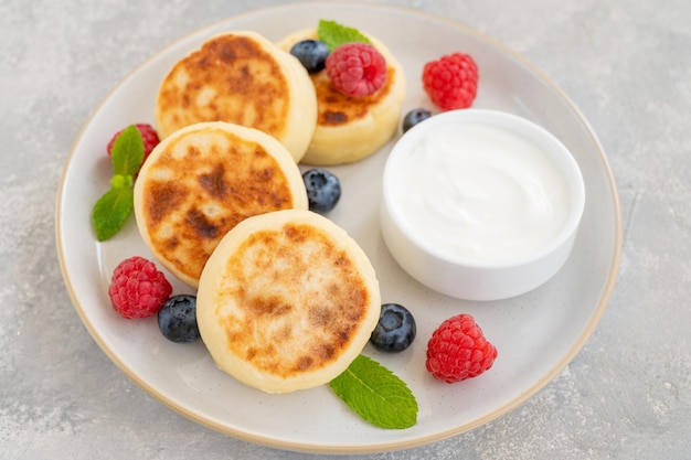 Cottage cheese pancakes with fresh berries sour cream and honey traditional Ukrainian syrniki