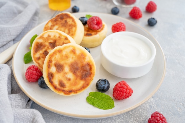 Cottage cheese pancakes with fresh berries, sour cream and honey