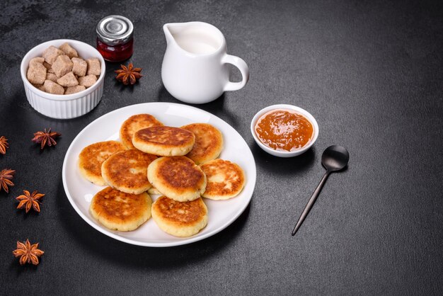 Cottage cheese pancakes with oats syrniki on a black rustic background