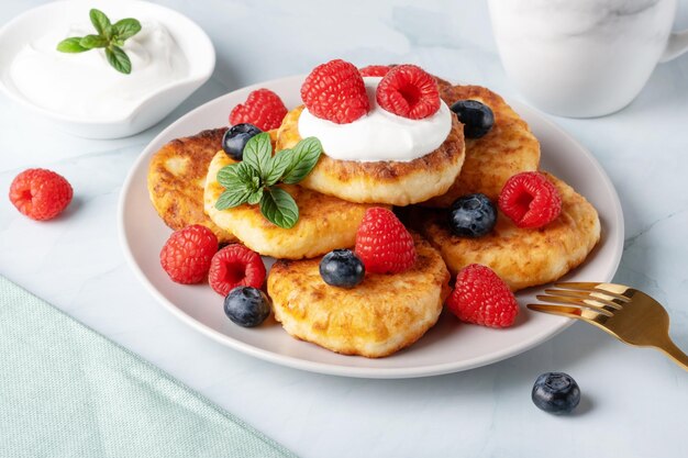 Cottage cheese pancakes with raspberries and blueberry on light background breakfast or lunch