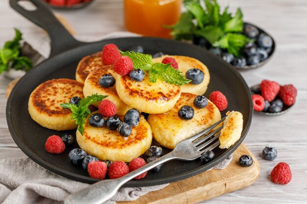 Frittelle di ricotta con lampone e mirtillo in padella su fondo rustico