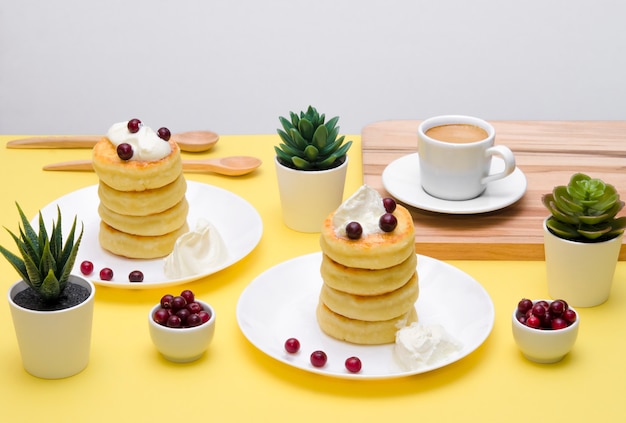 Foto frittelle di ricotta con panna acida e frutti di bosco su sfondo giallo. syrniki.