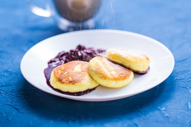 Cottage cheese pannenkoeken met kersenjam, close-up, bovenaanzicht. bestrooi met poedersuiker.