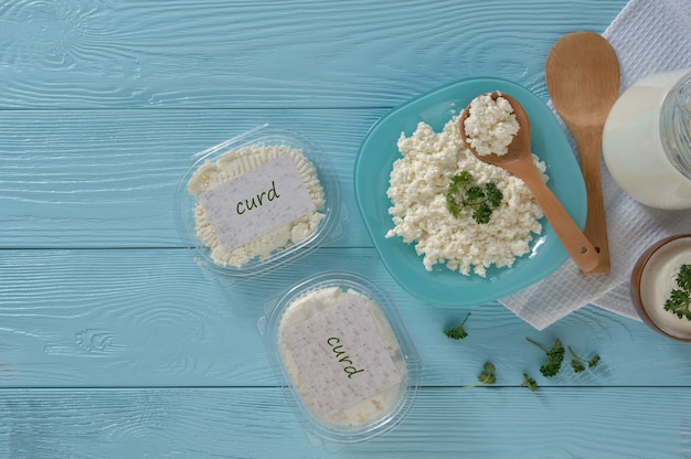 플라스틱 포장에 있는 코티지 치즈와 나무 파란색 배경에 있는 우유 건강한 식생활 개념