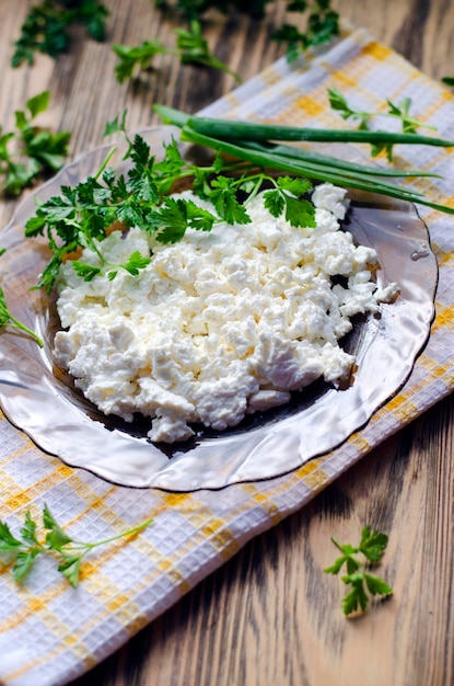 Cottage cheese in a plate on the table and fresh herbs