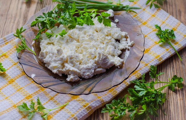 Cottage cheese in a plate on the table and fresh herbs