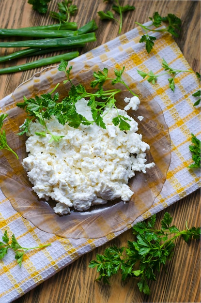 Cottage cheese in a plate on the table and fresh herbs