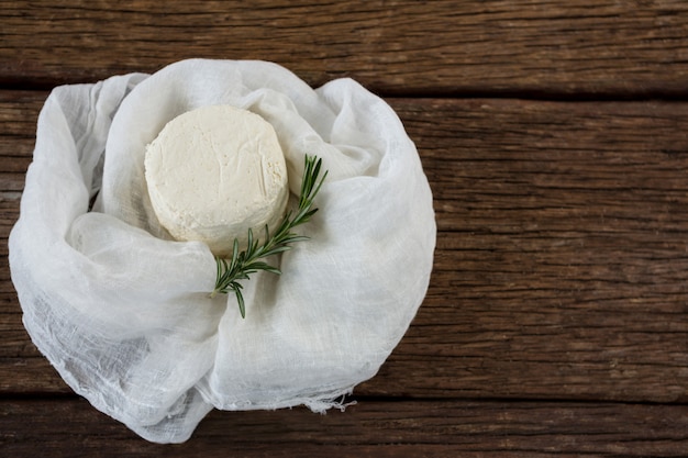 Cottage cheese and rosemary herb in white cloth on wooden board