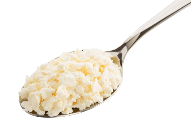 Cottage cheese in spoon on white surface