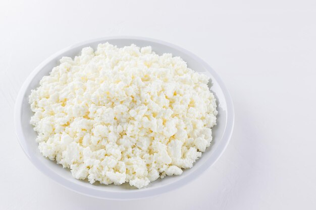 Foto cottage cheese su piatto bianco cottage fresh su sfondo bianco top view copy space