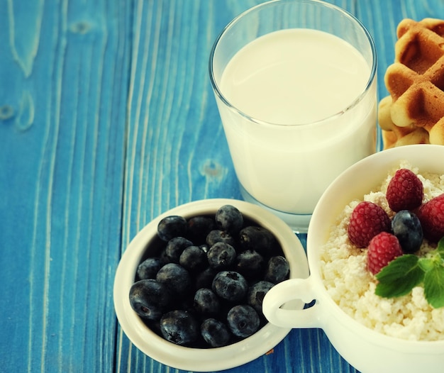 Cottage cheese with berries waffles and milk on a wooden blue background