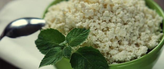 Cottage cheese with mint in a green bowl on a white napkin Top view