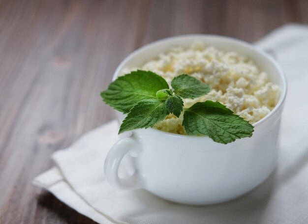 Cottage cheese with mint in white bowl close up