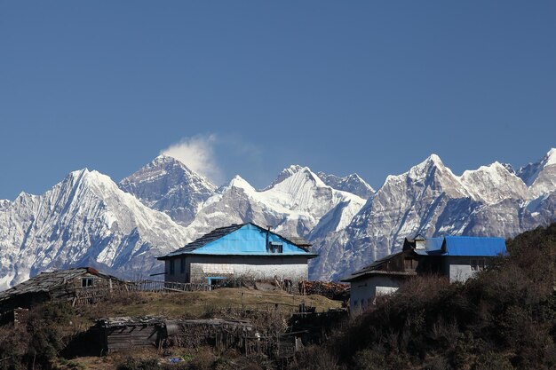 写真 晴れた空に照らされた小屋と雪に覆われた山