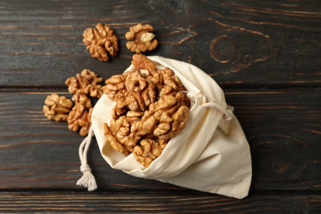 Cotton bag with tasty walnuts on wooden