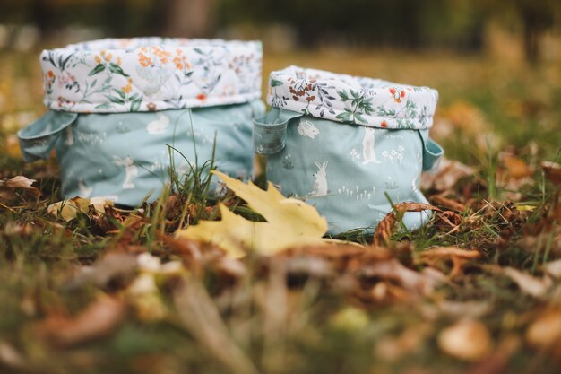 Cestini o sacchetti di cotone sull'erba tra le foglie autunnali su sfondo autunnale