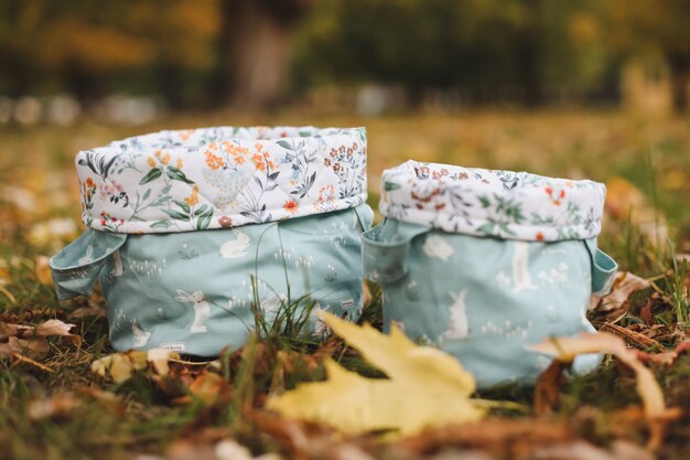 Cotton baskets or bags on the grass among autumn leaves on autumn backgroun