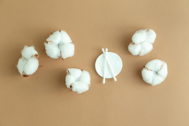 Cotton bolls and cotton pads for removing makeup on a beige background