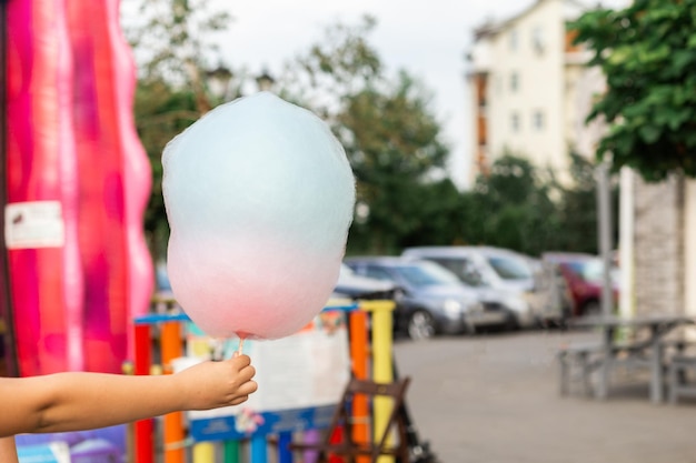 Cotton candy in a childs hand on a blurred background of the street