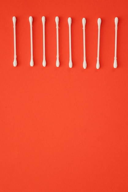 Cotton ear sticks for personal hygiene on red background Healthcare tools