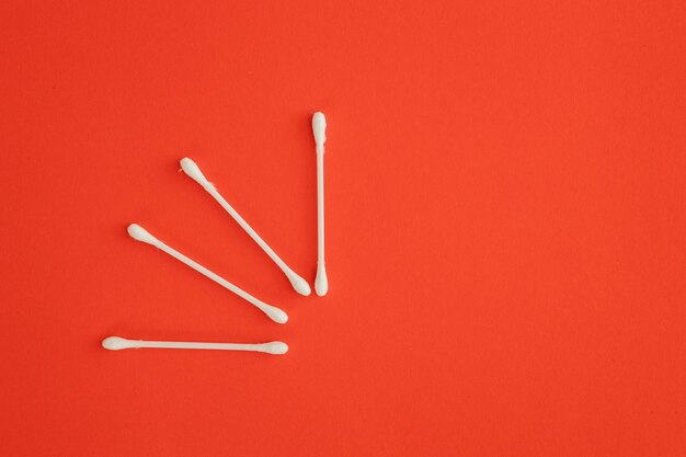 Cotton ear sticks for personal hygiene on red background Healthcare tools