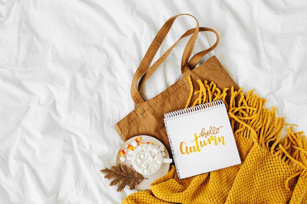 Cotton eco bag with cup of coffee and notebook on bed. autumn\
concept.