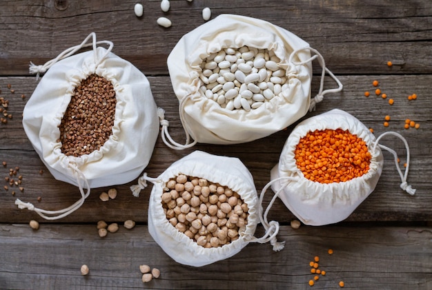 Cotton eco bags with dried raw healthy grain top view on rustic wooden table