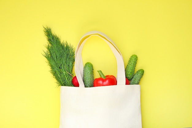 Foto sacchetto della spesa di eco del cotone con le verdure su fondo giallo vista superiore, spazio della copia.