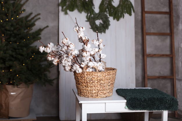 Fiori di cotone in un cestino. scandinavia. delicati fiori di cotone bianco. fiori di cotone all'interno della casa. cotone lanuginoso bianco secco in un cestino sul tavolo. interno di casa rustica. natale. nuovo anno.