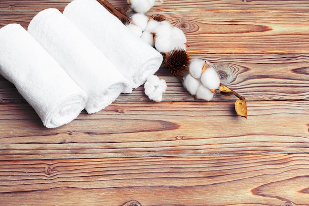 Cotton flowers with towel on wooden table