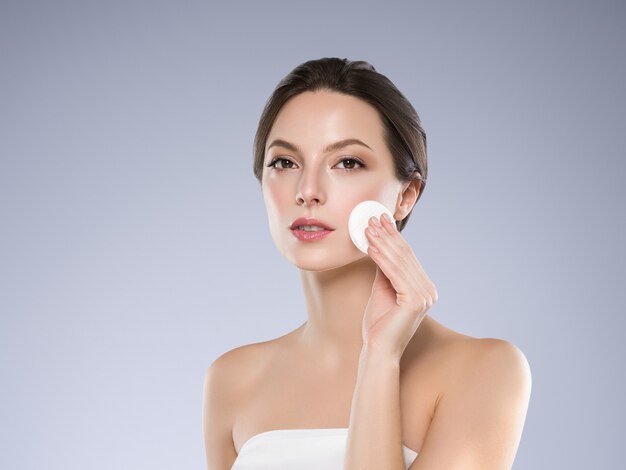 Cotton pad woman face clean skin emoving makeup. studio shot.
color background.