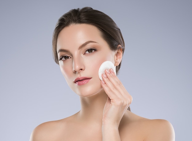Cotton pad woman face clean skin emoving makeup. studio shot.\
color background.