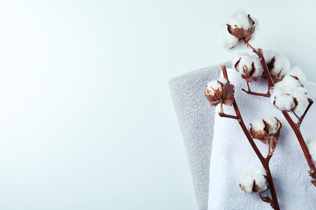 Cotton plant branches and towels on white surface