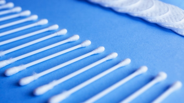 Cotton sticks and pads on a blue background, space for text