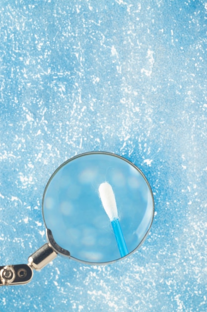 Cotton swab through magnifying glass, selective focus.