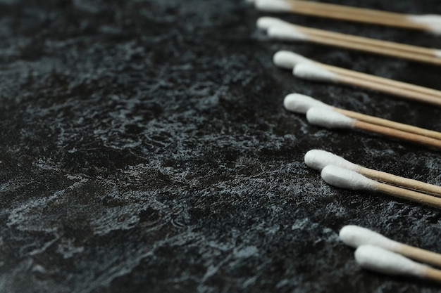 Cotton swabs on black smoky background, space for text