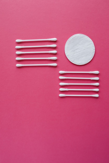 Photo cotton swabs and disks isolated on a pink background. hygiene products.