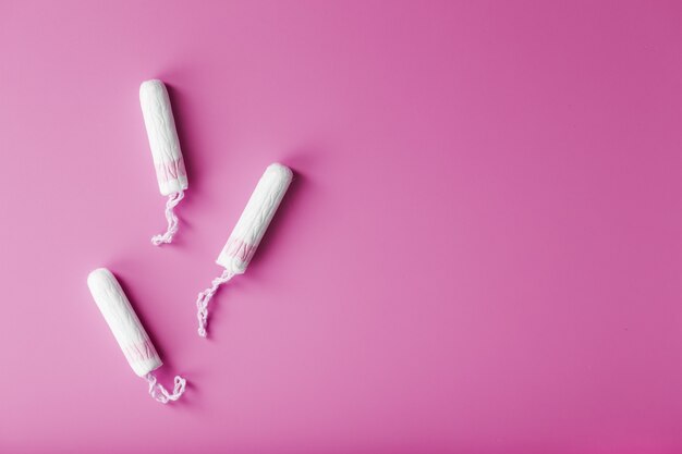 Cotton tampons on a pink background with a free space