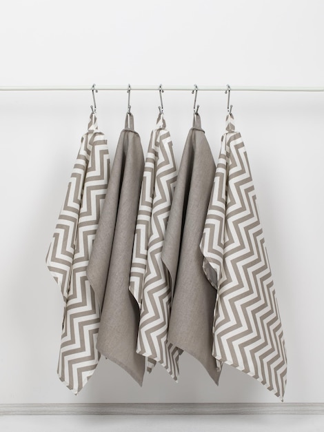 cotton waffle towels for the kitchen hang on hooks on a bracket against a white wall background