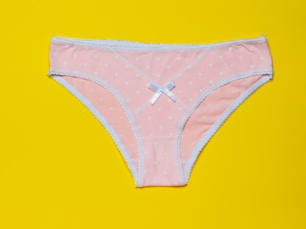 Cotton women's pink panties on a bright yellow surface