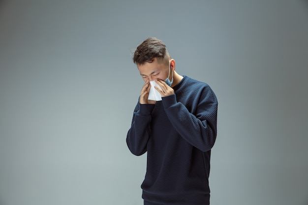 Cough, sneeze. Chinese man in blue protective mask posing. Prevention against pneumonia respiratory symptoms such as fever, headache. Chinese coronavirus illustration. Healthcare, medicine concept.