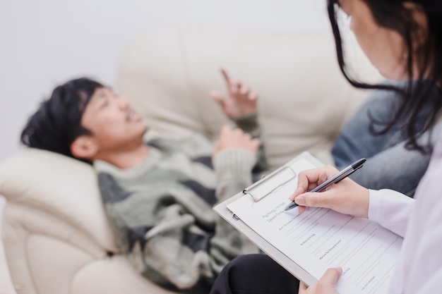 Photo counselor having therapy session with patient man lying at sofa and telling story to therapist